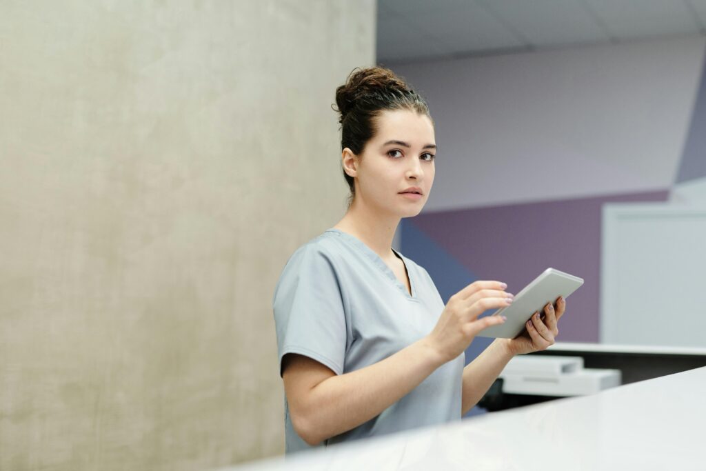 Healthcare receptionist using a tablet at a professional reception desk